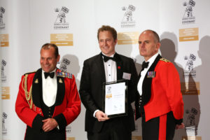 A man holding a certificate next to two guards. 