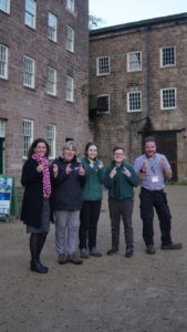 A group of men and women with their fingers crossed infront of a historical building