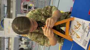 A young cadet building a miniature trestle A-frame